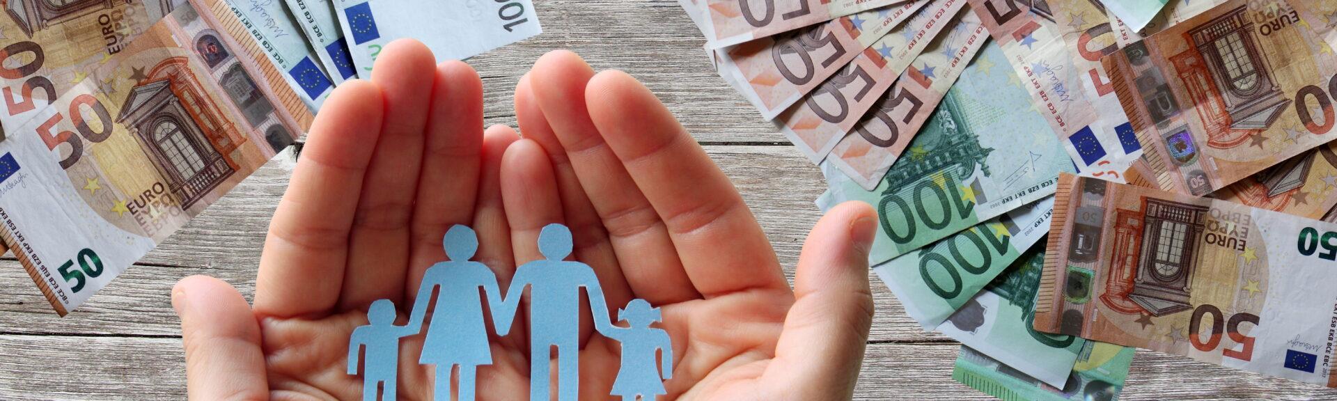 Paper family in hands on wooden background with euro banknotes