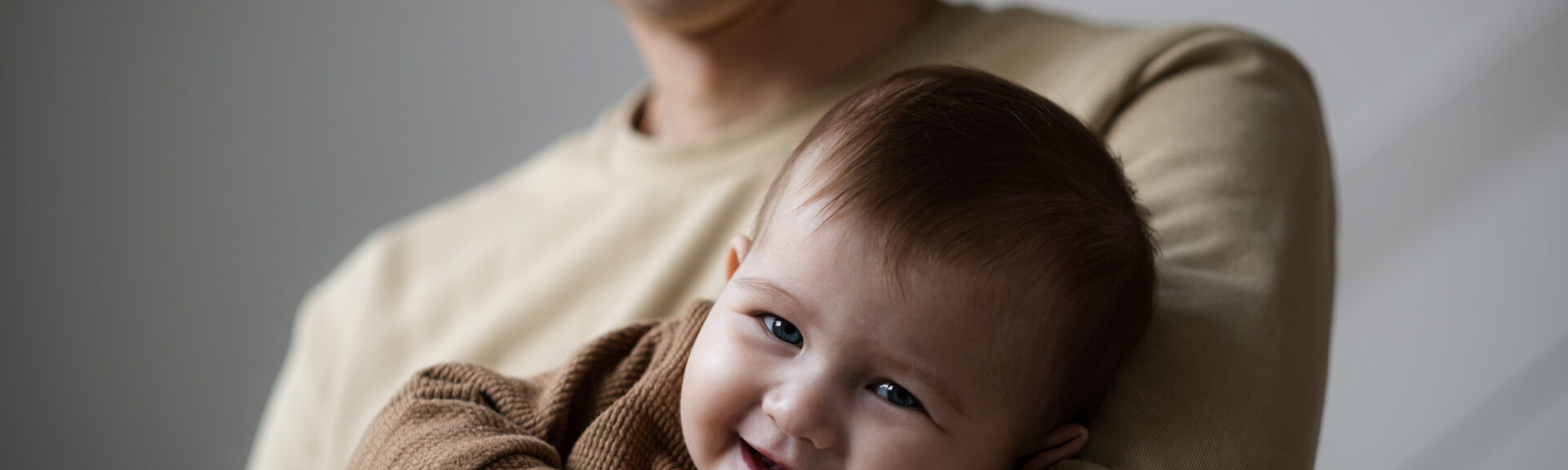 Man holding little five, six months baby smiling at home. Father and child indoors, Happy parenthood concept. Copy space